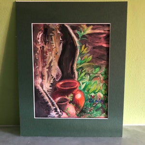 May include: Watercolor painting of two terracotta pots in a natural setting, framed with a green mat. The artwork features a dark background with hints of green foliage and a signature in the lower right corner.