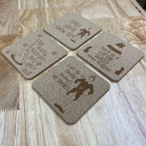 May include: Set of four cork coasters with Christmas-themed sayings and illustrations. The coasters feature sayings like "OMG! Santa I know him", "Bye buddy hope you find your dad", "Don't be a cotton headed ninny muggins", and "I just like to smile smiling's my favorite".