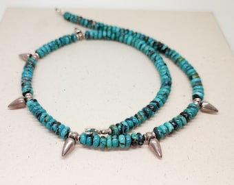 May include: A turquoise and silver necklace with pointed accents. The necklace is made of small, round turquoise beads and silver beads with pointed tips.
