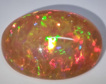 May include: A large, oval-shaped, orange opal gemstone with iridescent flashes of green, red, and blue.