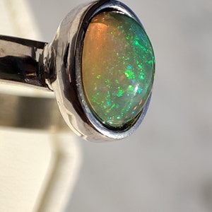 May include: A silver ring with a green and white opal gemstone.
