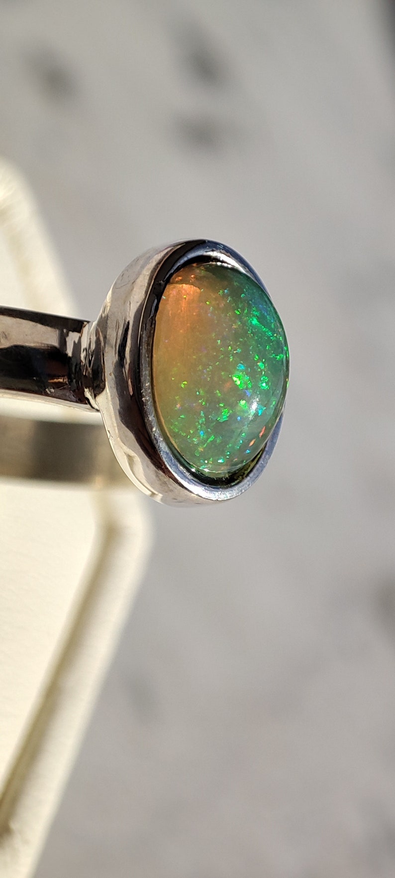 May include: A silver ring with a green and white opal gemstone.