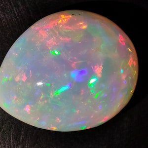 May include: A white opal gemstone with iridescent flashes of green, blue, pink, and orange.