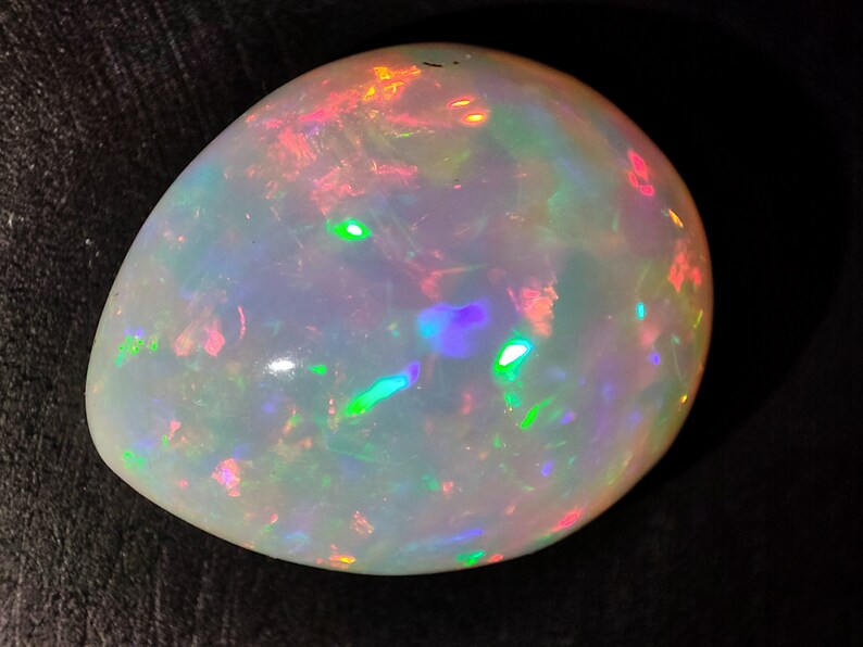 May include: A white opal gemstone with iridescent flashes of green, blue, pink, and orange.