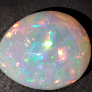 May include: A white opal gemstone with iridescent flashes of green, blue, pink, and orange.