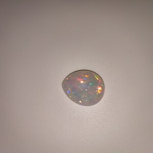 May include: A white opal gemstone with iridescent rainbow colors.