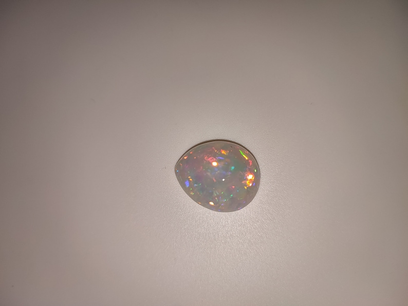 May include: A white opal gemstone with iridescent rainbow colors.