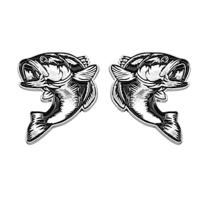 May include: Two black and white bass fish jumping out of the water, with a silver finish. The fish are facing opposite directions.