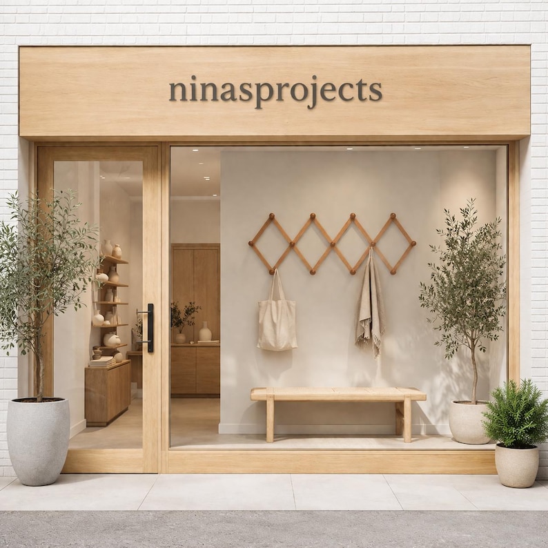 K&ouml;nnte beinhalten: Au&szlig;enansicht eines Gesch&auml;fts mit dem Namen "ninaprojects" &uuml;ber dem Eingang. Das Gesch&auml;ft verf&uuml;gt &uuml;ber eine Holzt&uuml;r und ein gro&szlig;es Glasfenster. Im Inneren sind eine Holzbank, ein Wandgarderobenst&auml;nder und eine Tragetasche zu sehen. Topfpflanzen flankieren den Eingang.