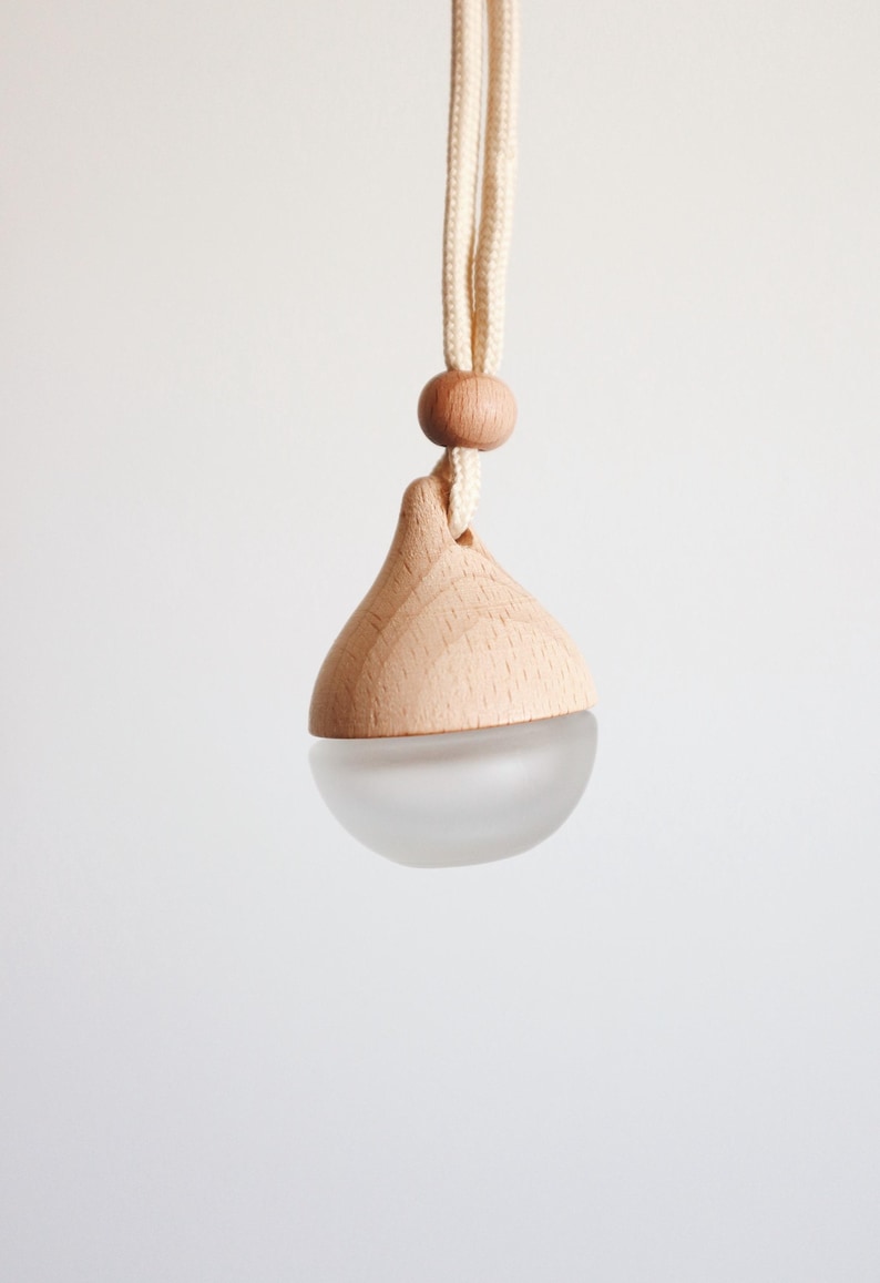 Puede incluir: Un colgante difusor de madera y vidrio con un cord&oacute;n blanco. El difusor tiene forma de l&aacute;grima y tiene un fondo de vidrio esmerilado.