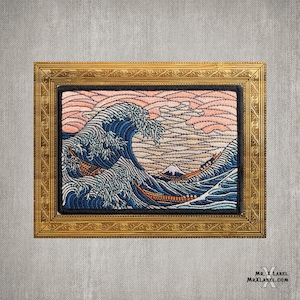 May include: A framed embroidered patch depicting the Great Wave off Kanagawa, a famous Japanese woodblock print by Hokusai. The wave is blue and white, with a pink and white sky in the background. The patch is framed in a gold frame.