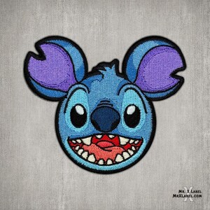 May include: Blue and purple embroidered patch of a cartoon character with big eyes and a wide open mouth, resembling Stitch from Lilo & Stitch.