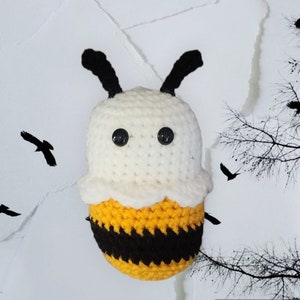 May include: A crocheted bee plush toy with a white head, black eyes, and a yellow and black striped body.