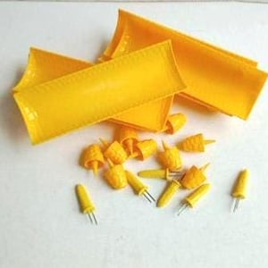 May include: A collection of yellow corn cob holders and individual corn holders. The corn cob holders are rectangular and folded. The individual holders are yellow with metal prongs.