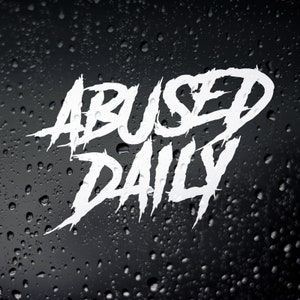 May include: White text on a black background reads "ABUSED DAILY" in a stylised, graffiti-like font. The background is blurred and appears to be covered in water droplets.