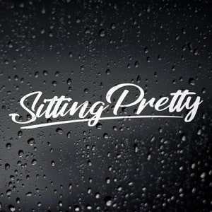 May include: White text on a black background that reads "Sitting Pretty" with raindrops on the surface.