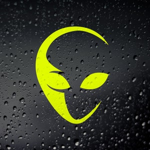 Peut inclure: Un autocollant de visage extraterrestre jaune sur un fond noir avec des gouttelettes d'eau.