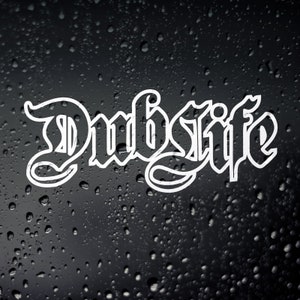 May include: White vinyl decal with the word "Dublife" written in a gothic font. The decal is on a black background with water droplets.