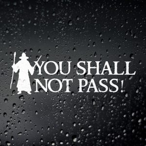 Peut inclure: Autocollant en vinyle blanc avec la silhouette d'un magicien et le texte "YOU SHALL NOT PASS !" sur fond noir avec des gouttelettes d'eau. Un article décoratif pour les fans de littérature et de films fantastiques.