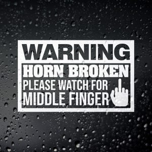 May include: White rectangular sticker with black text that reads "WARNING HORN BROKEN PLEASE WATCH FOR MIDDLE FINGER" and a graphic of a hand with the middle finger extended. The sticker is on a black background with water droplets.