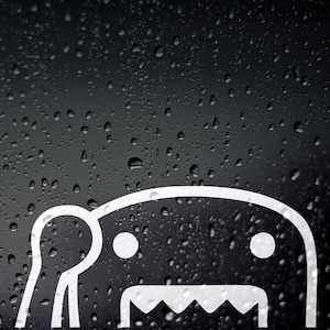 Pode incluir: Um adesivo branco de um monstro de desenho animado com uma boca grande e dois olhos em um fundo preto com gotas de água.