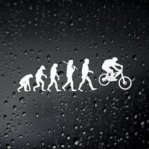 May include: White vinyl decal showing the evolution of man to a mountain biker. The design progresses from ape to a person on a bicycle. The decal is on a black background with water droplets.