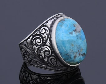 May include: A silver ring with an ornate design and a large turquoise stone.