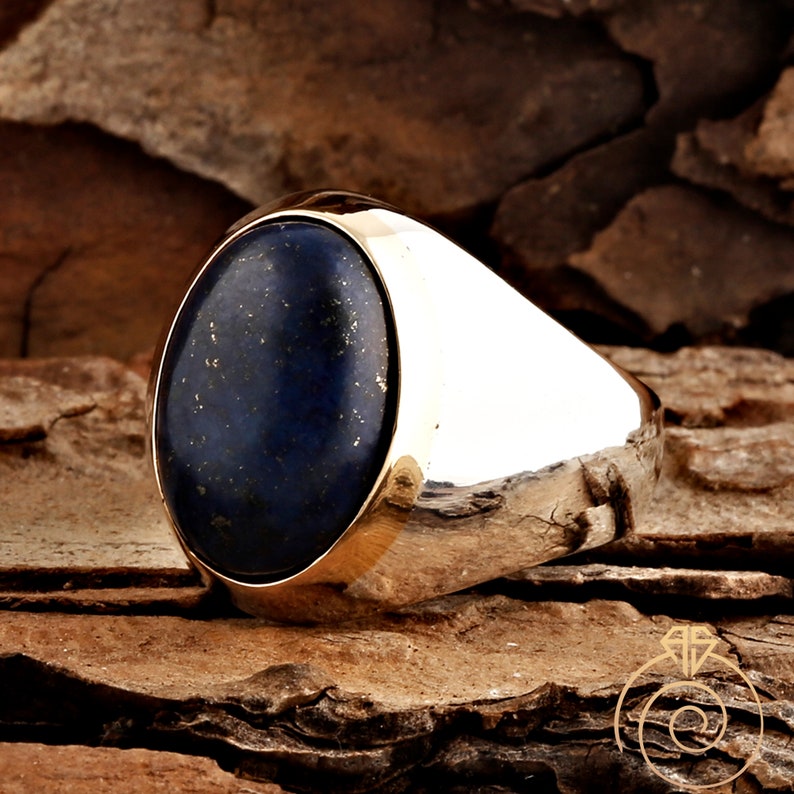 May include: A silver ring with a large oval-shaped lapis lazuli gemstone. The ring has a polished silver band and a smooth, rounded top.