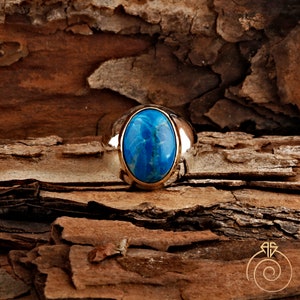 K&ouml;nnte beinhalten: Ein silberner Ring mit einem gro&szlig;en ovalen blauen Edelstein, der in der Mitte eingesetzt ist.