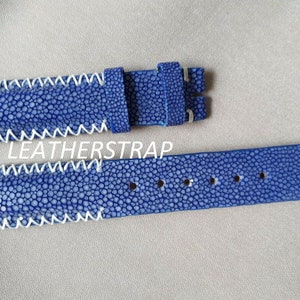 Può includere: Cinturino per orologio in pelle di razza blu con cuciture bianche. Il cinturino è largo 20 mm e ha un'asta a molla a sgancio rapido.