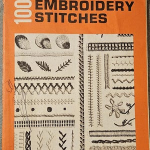 May include: A vintage orange booklet titled "One Hundred Embroidery Stitches" by Coats & Clark's. The cover features a variety of black and white embroidery stitches, including leaves, flowers, and geometric patterns. The book is numbered 150 and priced at 35 cents.