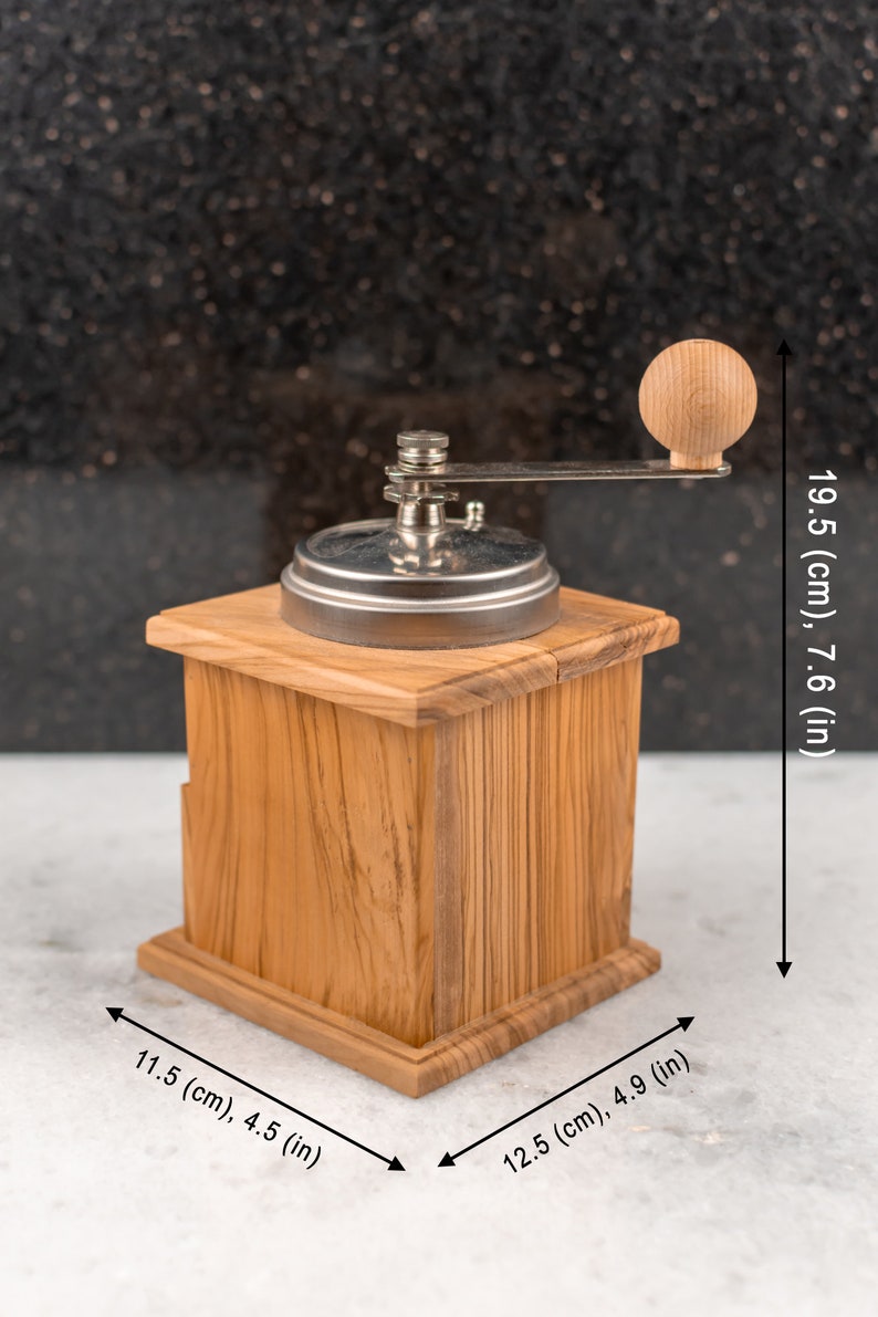May include: A wooden manual coffee grinder with a silver metal grinder and a wooden crank handle. The grinder is 7.6 inches tall, 4.5 inches wide, and 4.9 inches deep.