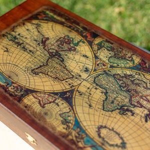May include: A wooden box with a vintage world map design on the lid. The map is in shades of brown, green, and blue, with a detailed grid pattern.