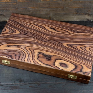 May include: A wooden box with a dark brown wood grain pattern and brass hinges. The box is closed.