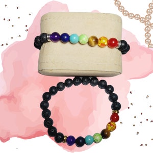 May include: Two beaded bracelets. One bracelet features black lava beads with a row of colorful chakra beads. The other bracelet has black lava beads with a row of colorful chakra beads. The bracelets are displayed on a beige stand.