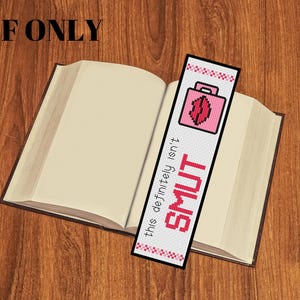 May include: A bookmark with a pink pixelated design and the text "this definitely isn't SMUT" is placed in an open book. The bookmark features a pink briefcase and a pixelated design of lips.