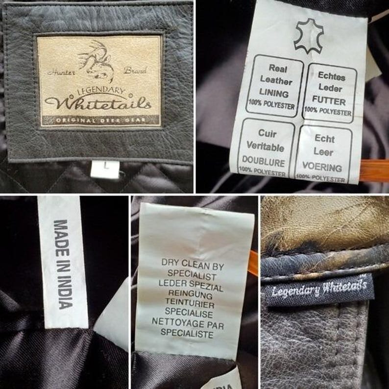Op de afbeelding: Close-up van een zwarte leren jas met meerdere labels. E&eacute;n label luidt "LEGENDARY Whitetails ORIGINAL DEER GEAR". Andere labels geven "Echt Leer" en "Made in India" aan. De jas heeft een gewatteerde voering.
