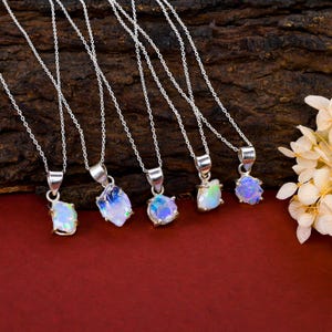 May include: Six silver necklaces with opal pendants. The opals are all different shapes and sizes and have a rainbow of colors.
