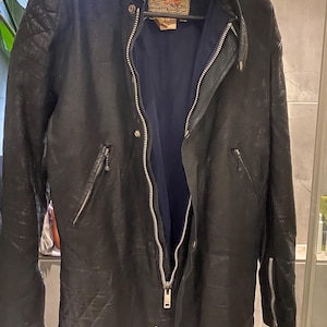 Puede incluir: Chaqueta de moto de cuero negro con cremallera completa, múltiples bolsillos con cremallera y diseño de hombros acolchados. La chaqueta tiene una etiqueta Champion Clothing Rivetts.