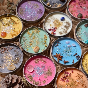 Puede incluir: Surtido de velas coloridas en frascos de vidrio con diversos elementos naturales y cristales. Las velas están dispuestas en círculo sobre una superficie de madera rústica.
