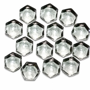 May include: A collection of fourteen clear, hexagonal glass cabochons arranged in a cluster. Each piece features a smooth, faceted top surface and a textured, slightly frosted underside, creating a reflective and translucent appearance throughout.