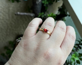May include: A gold ring with a red oval gemstone.