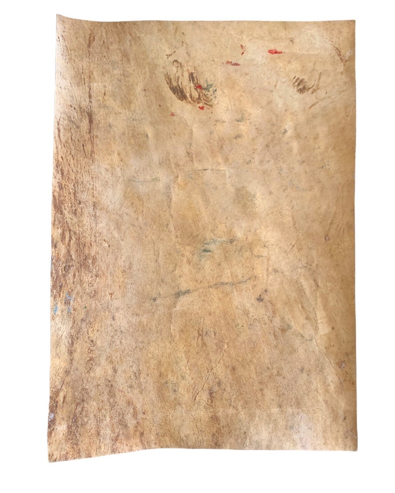 以下が含まれることがあります： 薄茶色の長方形の、古びた質感の紙。紙には折り目やシミが目立ち、赤と緑の小さなペイントの跡がある。端はわずかにカールしており、古さと使用感を示唆している。