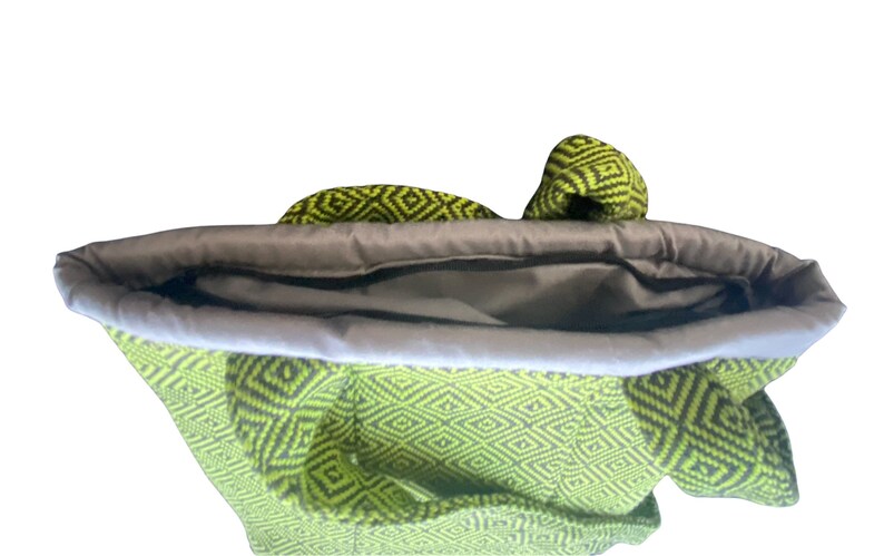 Puede incluir: Una bolsa de mano de color verde y negro con un forro gris. La bolsa est&aacute; abierta y el forro es visible.