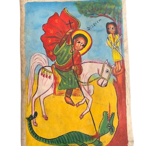 以下が含まれることがあります： 手描きのエチオピアのイコン。白い馬に乗った人物が緑のドラゴンを倒している様子が描かれています。その人物は赤いマントと緑のチュニックを着ています。黄色い服を着た人が木に縛られています。背景は黄色と青です。