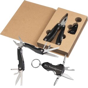 Könnte beinhalten: Zwei Multifunktions-Taschenmesser in einer Kartonbox. Ein Messer ist geöffnet und hat einen schwarzen Griff mit silbernen Klingen. Das andere Messer ist geschlossen und hat einen schwarzen Griff mit einem silbernen Schlüsselring. Die Box ist braun und hat ein weißes Etikett mit der Aufschrift "Ihre Wunschgravur".