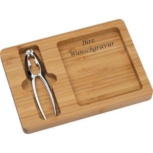 Könnte beinhalten: Ein Holztablett mit einem integrierten Nussknacker. Das Tablett hat einen rechteckigen Platz für eine Gravur mit dem Text "Ihre Wunschgravur".
