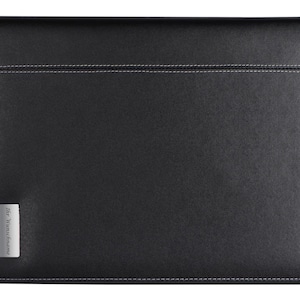 Könnte beinhalten: Schwarze Lederhülle für Laptops mit einem silbernen Etikett mit der Aufschrift "Hermès Paris".