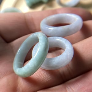 May include: Three jade rings, two are light blue and one is a pale green. The rings are stacked on top of each other.