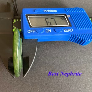 May include: A close-up of a green jade pendant being measured with a digital caliper. The caliper reads 6.7 mm. The text "Best Nephrite" is visible below the pendant.